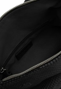 Borsa nera con un'esterno texture ispirata ai rettili. L'interno presenta una fodera in tessuto nero e una tasca con zip per l'organizzazione.