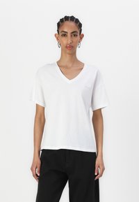 Hvid bomulds V-hals t-shirt med korte ærmer og en afslappet pasform, der har et diskret logo på brystet. Enkel og minimalistisk design.