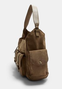 Sac à épaule en suede marron avec poche à rabat à l'avant, poches latérales avec boucles, compartiment zippé et large bandoulière en cuir.