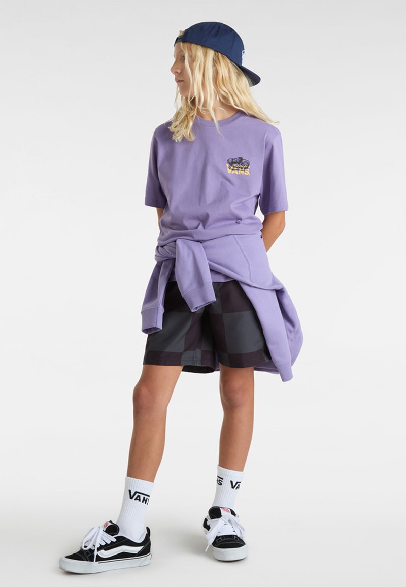 Fialová košile s logem Vans, šedé a černé kostkované šortky, bílé ponožky s textem Vans, černé boty a modrá kšiltovka. Neformální outfit.