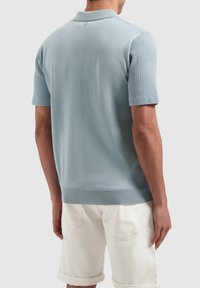Lichtblauw gebreid poloshirt met een structuurdesign op de schouders en korte mouwen, afgewerkt met een geribde kraag en zoom.