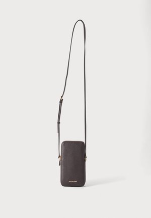 Petit sac téléphone bandoulière en cuir marron foncé avec longue sangle ajustable et fermeture éclair dorée sur fond clair uni.