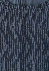 Gros plan sur un tissu foncé avec un motif de rayures verticales bleues irrégulières et une ceinture froncée en haut.