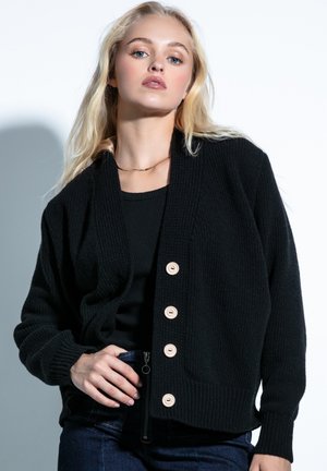 Czarny kardigan z teksturowanej dzianiny z dekoltem w kształcie litery V, z pięcioma dużymi beżowymi guzikami i szczegółem w postaci kieszeni zapinanej na zamek.