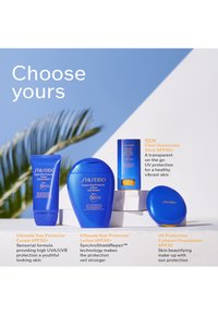 Neljä sinistä Shiseido-aurinkosuojatuotetta, joissa on SPF50+ ja SPF30, esillä valkoisella pinnalla sinivalkoista taustaa vasten.