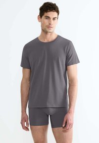 T-shirt grigio in cotone con maniche corte e scollo rotondo, abbinato a pantaloni sportivi grigi in coordinato, caratterizzati da una texture liscia.