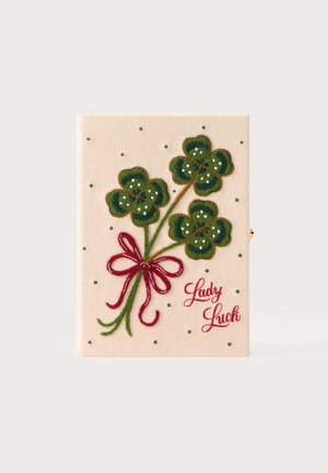 Beżowa tkanina z naszytymi trzema zielonymi czterolistnymi koniczynami związanymi czerwoną kokardą oraz słowami "Lady Luck" na czerwono.