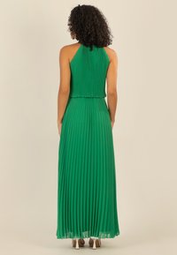 Grünes, plissiertes Maxikleid mit hohem Halterneck, fließendem Rock und durchscheinendem Saum; strukturierter Stoff mit gleichmäßig verteilten vertikalen Falten.