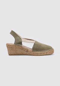 Sandalia de cuña tipo slingback en ante verde oliva, con una correa elástica, tacón de yute trenzado y detalles de costura a lo largo del borde.