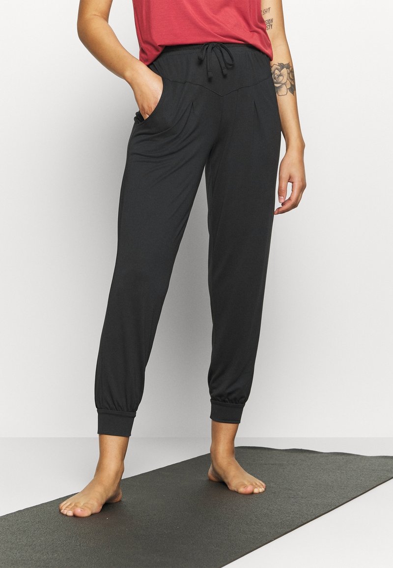 Sorte bukser lavet af blødt stof, med en elastisk talje og snoretræk, sidelommer og stoppede manchetter ved anklerne.