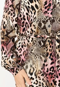 Abito in stampa leopardata realizzato in un tessuto morbido, con sfumature di rosa, marrone e nero, dettagli con bottoni e vita legata per una silhouette aderente.