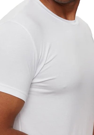 T-shirt blanc à manches courtes fabriqué dans un tissu doux et extensible ; col rond à bords lisses ; design ajusté mettant en valeur les contours des bras et des épaules.