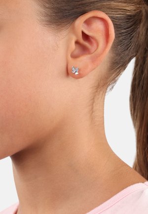 Orecchino a perno a forma di farfalla in argento con ali dettagliate, posizionato su un tono di pelle uniforme, che mette in risalto una finitura lucida e una leggera scintillio.