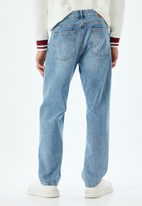 Jeans in denim azzurro chiaro con taglio dritto, design a cinque tasche e leggeri sbiadimenti; doppie tasche posteriori e una toppa in pelle in vita.