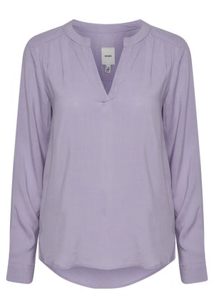 Levandų spalvos ilgio rankovėmis bluzonas su V formos iškirpte, turintis raukšles prie pečių ir apvalų apatinį kraštą. Pagamintas iš lengvos, lygios medžiagos.