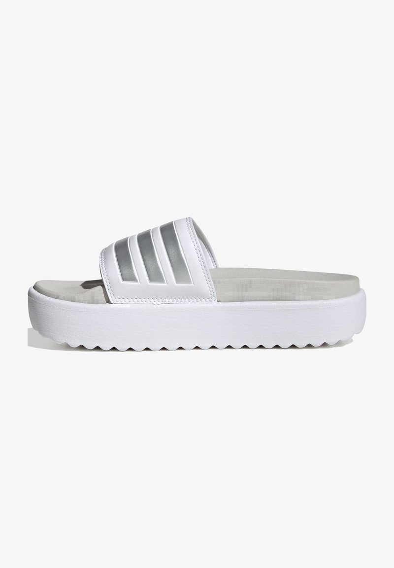 White slide sandals in synthetic material with a wide strap featuring silver horizontal accents. Thick white sole with zigzag pattern.