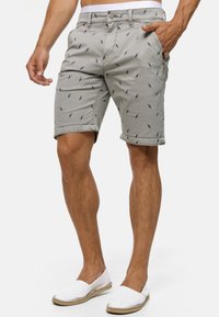 Shorts en coton gris avec un motif d'oiseaux, dotés de poches latérales et d'un ourlet roulé, complétés par une taille blanche et une quincaillerie simple.