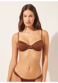 Braunes Bikini-Set mit gerafftem Design und verstellbaren Trägern. Der trägerlose Oberteil hat ein zentrales Knotendetail und wird mit passendem niedrig geschnittenem Höschen kombiniert.