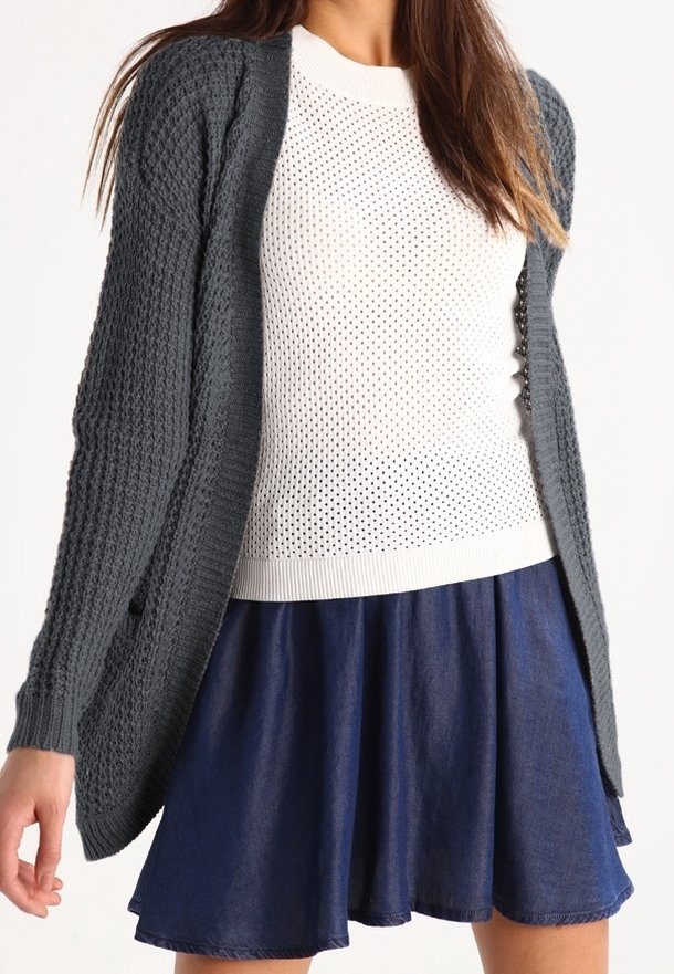 Stickad mörkgrå cardigan med öppen framsida, strukturerat mönster, tillsammans med en vit perforerad tröja och en marinblå utsvängd jeanskjol.