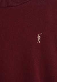 Burgunderfarbenen gestrickten Pullover mit einem gerippten Rundhalsausschnitt und einem kleinen beigen Logo eines Golfspielers auf der linken Seite. Weiche Textur, figurbetonte Passform.