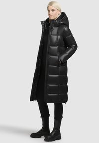 Black puffer coat with a hood, featuring a quilted design, shiny finish, zippered pockets, and a long silhouette.