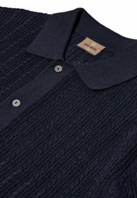 Navy blue knitted polo shirt with ribbed collar and button placket, featuring textured cable knit pattern and silver buttons.
