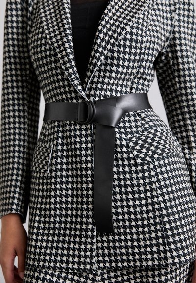 Fekete-fehér houndstooth mintás blézer, kivágott gallérral, széles fekete bőr övvel és folt zsebekkel.