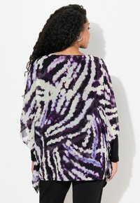 Kimono trasparente con un motivo tie-dye viola e nero, design fluido, maniche larghe e vestibilità morbida, abbinato a pantaloni neri.