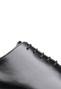 Zwarte leren schoen met een gladde afwerking, voorzien van decoratieve veters en tonal stiksels langs de rand. Het ontwerp is strak en minimalistisch.