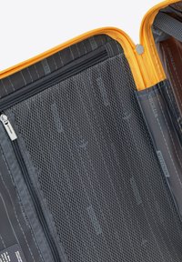 Interno di una valigia arancione con zip, caratterizzato da tasche in rete nera e tessuto liscio. Comprende dettagli di marca e sezioni organizzative sottili.