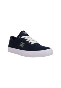 Navy blue canvas sneakers feature a white rubber sole, white laces, and a silver logo on the side, with a rounded toe and textured accents.