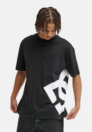 Czarny t-shirt z krótkim rękawem wykonany z bawełny, z dużym białym nadrukiem na dolnej części przodu, okrągłym dekoltem i luźnym krojem.