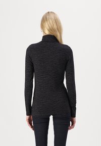 Zwarte lange mouwen top met een hoge kraag en een geweven zebra patroon, gemaakt van een zachte stof. Het heeft een slim fit ontwerp.