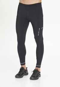Sorte trænings leggings lavet af et strækbart materiale, med en sidelomme i mesh og kontrasterende hvide detaljer, designet til komfort og bevægelse.