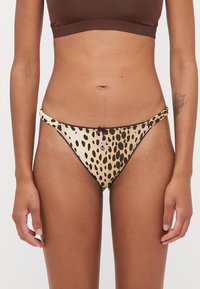 Bas de bikini imprimé léopard en beige et marron, avec une coupe basse, de fines bretelles latérales et un petit nœud à l'avant.