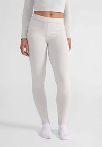 Leggings gris claro con una textura suave y elástica. Cintura alta y un diseño ajustado, acompañados de calcetines blancos hasta el tobillo.