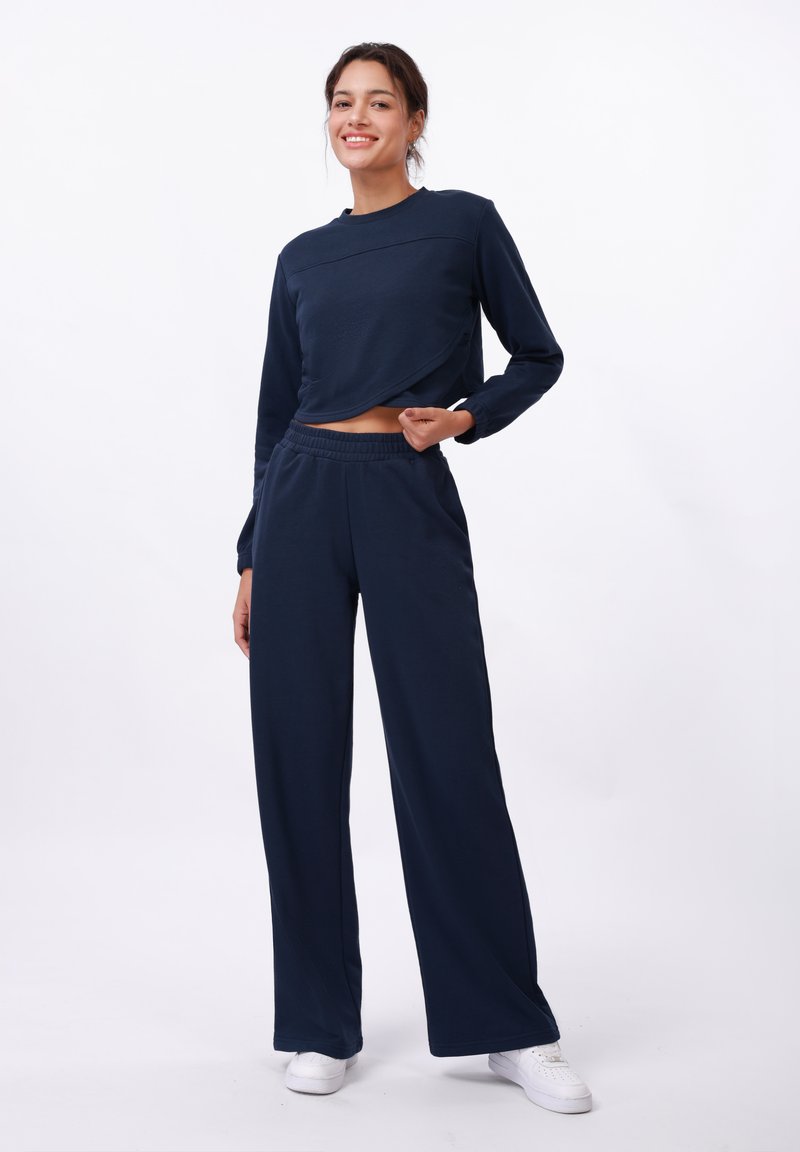 Haut court à manches longues bleu marine avec un col rond, associé à un pantalon large. Fabriqué en tissu doux, avec une taille élastique.