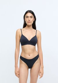 Set di bralette e perizoma nero. La bralette presenta un collo a V, spalline sottili e una texture liscia. Il perizoma ha un design minimalista e bordi senza cuciture.