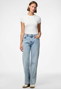 Bijela majica kratkih rukava u kombinaciji s svijetloplavim širokim trapericama. Traperice imaju visoki struk, prednje džepove i suptilno izblijeđivanje.