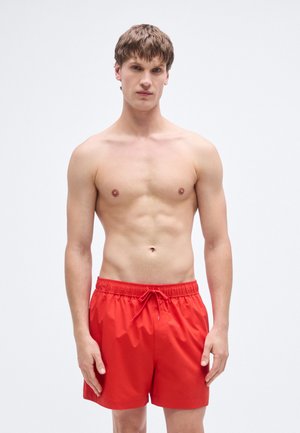 Pantaloncini da bagno rossi in tessuto leggero, con vita elasticizzata e coulisse, lunghezza sopra il ginocchio e texture liscia.