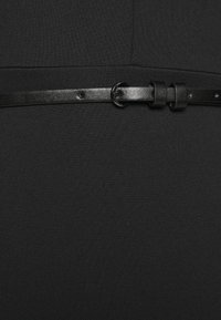 Tissu de robe noir avec un design ajusté et une texture. Comprend une ceinture en cuir noir étroite avec une boucle en métal ronde, fixée par des passants.