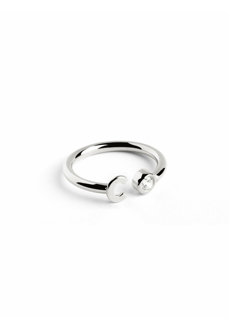 Anello in argento con un design aperto, caratterizzato da una lettera "C" su un'estremità e una pietra preziosa trasparente sull'altra. Superficie liscia e lucida.