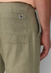 Licht khaki broek met een rechte snit, vervaardigd uit een gestructureerde stof, met een achterzak met een logotag en zichtbare stikdetails.