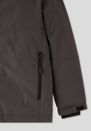 Parte di giacca impermeabile grigia con tasca con zip, texture del tessuto elegante e polsini elasticizzati per una vestibilità sicura.