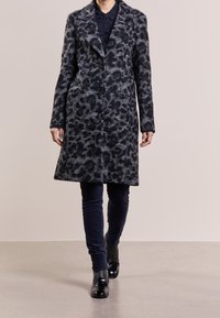 Wollen blendjas met een grijs en zwart luipaardprint, voorzien van een geknoopte kraag, twee voorzakken en een enkele knoopsluiting.