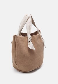 Sac fourre-tout en tissu marron texturé avec poignées crème nouées, forme arrondie et ouverture sans fermeture. Design simple avec peu d'ornements.