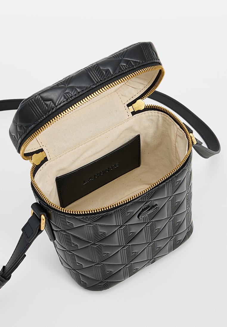 Sac en nylon noir avec un motif géométrique texturé, fermeture éclair dorée et intérieur beige. Dispose d'une poche pour carte noire à l'intérieur.