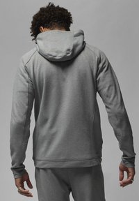 Felpa grigia con cappuccio, dal texture morbido, caratterizzata da maniche raglan, cappuccio regolabile con cordino e tasche laterali.