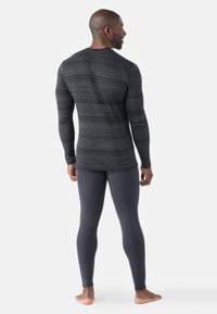 Donkergrijze thermo-top met lange mouwen en een subtiel streeppatroon, gecombineerd met bijpassende strakke legging, gemaakt van zachte, rekbare stof.