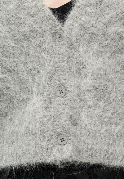 Ανοιχτό γκρι αφράτο ζακέτα με V-λαιμόκοψη, που διαθέτει πέντε στρογγυλά γκρι κουμπιά και μαλακή, υφή υφασμάτων.